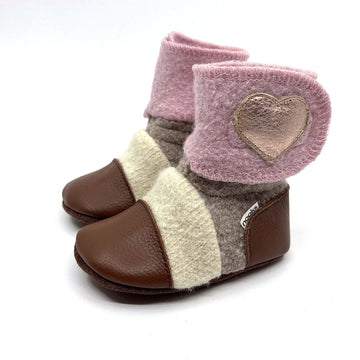 A pair of toddler booties with a color-blocked design featuring dusty pink, cream, taupe, and brown sections, with a metallic rose gold heart patch on the cuff.
